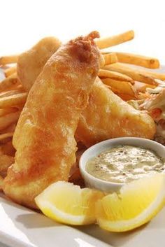 fried fish with dipping sauce and lemon wedges