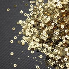 gold and black sequins are scattered on a metallic surface with holes in the middle