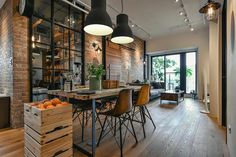 an open concept living and dining area with wood flooring, exposed brick wall, large windows, black pendant lights