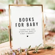 a sign that says books for baby next to some flowers and greenery on a wooden table