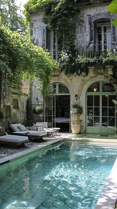 an outdoor swimming pool with chaise lounges next to it and ivy growing on the walls