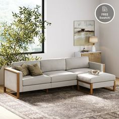 a living room scene with focus on the sectional sofa and footstool in the foreground