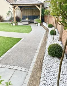 a backyard with grass, gravel and wooden benches in the back yard is well maintained