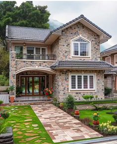 a house that is in the middle of some grass and flowers on the front lawn