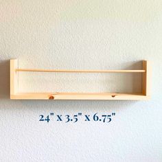 a wooden shelf mounted to the side of a white wall with measurements for each shelf