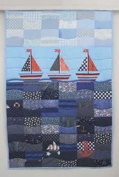 three sailboats are depicted on a quilted wall hanging in a white walled room