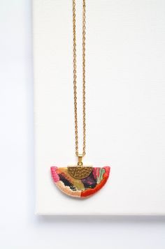 a necklace that has a small piece of jewelry hanging from it's end on a gold chain