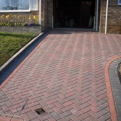 a brick driveway in front of a house with an open garage door on the side