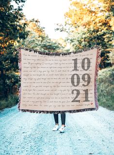 a person standing on a road holding a sign with the number twenty nine in front of them