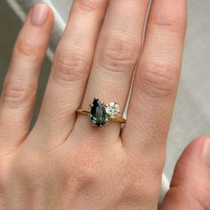 a woman's hand with a ring on it and two diamonds in the middle