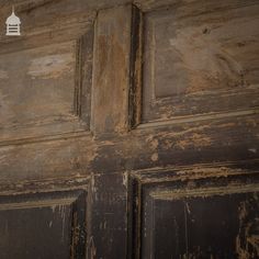 an old wooden door with peeling paint and a white light on top of the door