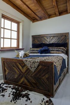 a large bed sitting under a window next to a cow's head on top of a rug