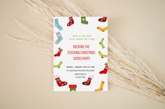 a christmas party card with stockings and socks on it, next to some dry grass