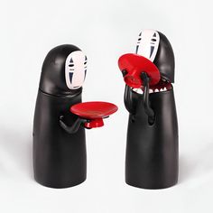 two black and red objects with faces on them, one has a plate in the other's mouth