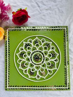 a green tray with a flower design on it next to some pink flowers and candles