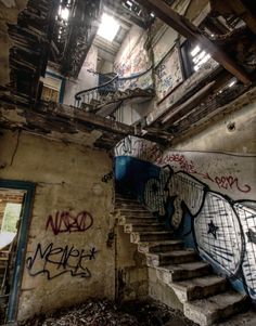 an abandoned building with graffiti on the walls and stairs