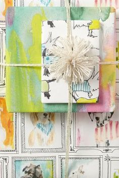 three wrapped presents tied up on top of each other in front of colorful wallpaper