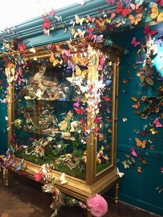 a display case filled with lots of different types of paper butterflies on the wall behind it