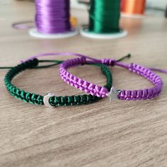 two bracelets sitting on top of a table next to spools of thread