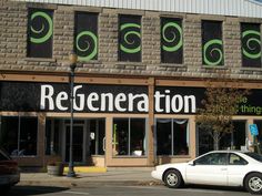 a white car is parked in front of a building with green lettering on the side