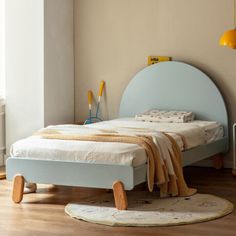 a bed sitting on top of a hard wood floor next to a wall mounted heater