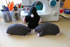 two stuffed animals sitting on top of a table next to a sewing machine and scissors