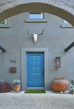 an entrance to a building with a blue door and cow skull mounted on the wall