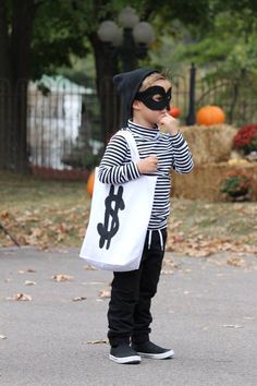 a little boy dressed up as a bag with a dollar sign on it and wearing a mask