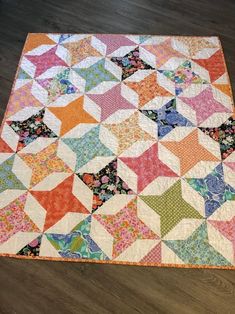 a multicolored patchwork quilt on a wooden floor