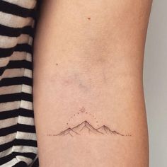 a woman's arm with a small mountain tattoo on the left side of her body