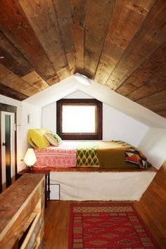 two beds in a loft with wooden floors and walls, along with a rug on the floor