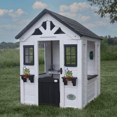 a small white and black play house with potted plants