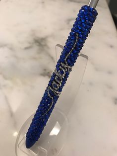 a blue and silver pen sitting on top of a glass stand next to a marble counter