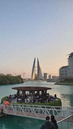 people are walking across a bridge over the water