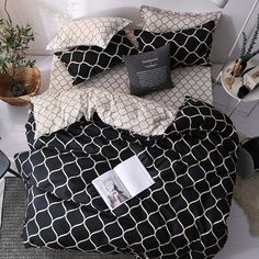 a bed with black and white comforter on top of it next to a potted plant