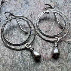 "I have carefully wrapped two sterling silver teardrops in sterling silver wire. The small teardrops dangle below sterling silver circles which I have formed, soldered, and hammered by hand. The earrings hang from handmade sterling silver earwires. Total Earring Length from the top of the ear wire to the bottom of the teardrop is just under 2 inches long. Outer Circle Measures about 1 inch across. Be sure to see all photos and video for size and finish reference. Select your desired finish when Teardrop Hoop Earrings, Long Outer, Black Pearl Earrings, Silver Chain Earrings, Chalcedony Earrings, Silver Pearl Earrings, Natural Stone Earrings, Teardrop Dangle Earrings, Hammered Sterling Silver