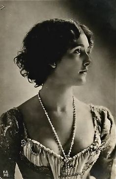 an old black and white photo of a woman in a dress with pearls on her neck