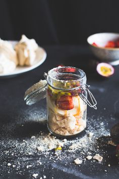 a glass jar filled with food sitting on top of a black table next to other dishes