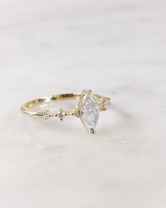 a gold ring with a pear shaped diamond and three small round diamonds on the side