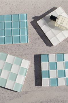 four pieces of blue and white tile with a bottle of perfume on the ground next to them