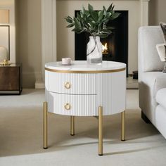 a white and gold side table with a vase on it in front of a fireplace