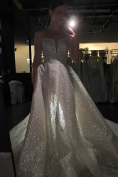 a woman standing in front of a mirror wearing a wedding dress with sequins on it