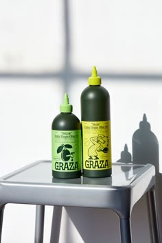 two green and yellow bottles sitting on top of a metal table next to each other