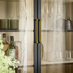 the glass shelves are filled with bottles and glasses