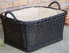 a wicker basket sitting on the ground next to a brick wall