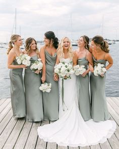 a group of women standing next to each other on a wooden dock near the water