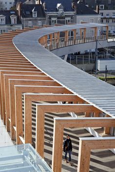 a person walking down a wooden walkway in front of some buildings and houses with lots of wood slats on the sides