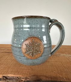 a blue mug with a snowflake design on the side sitting on a wooden table