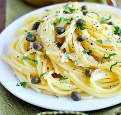 a white plate topped with pasta and olives