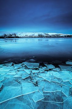 black and white photograph of ice floes on the water with mountains in the background